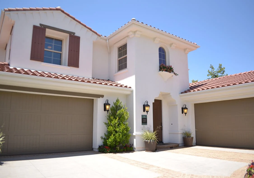 A white concrete two-storey house with a garage door