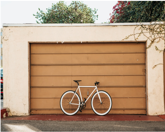 Bike parked leaning against a garage door.