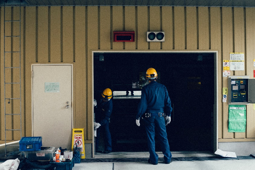 Two technicians conducting repairs on a garage door.