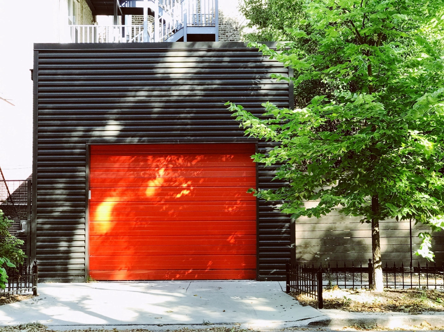 A bright orange garage door stands out against a black building