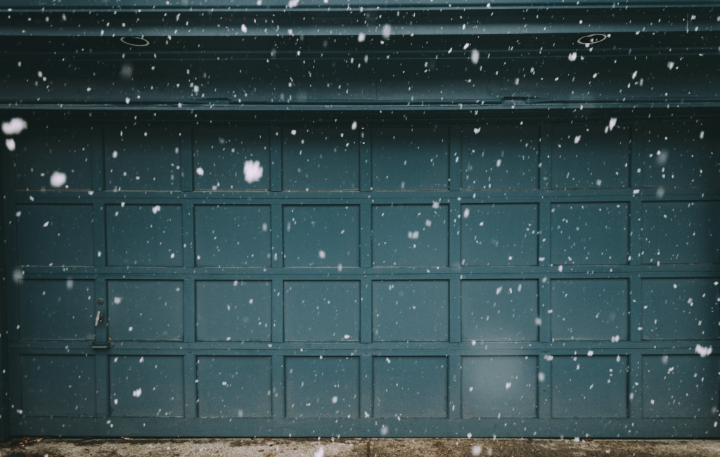 Snowflakes fall against a blue garage door
