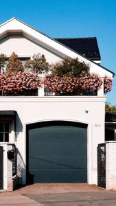 A modern house with flowers on a balcony and black garage door